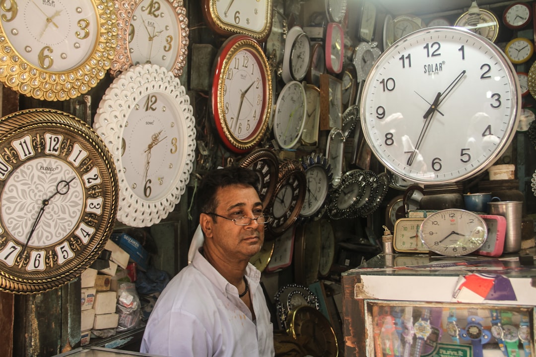 a man standing in front of a wall of clocks