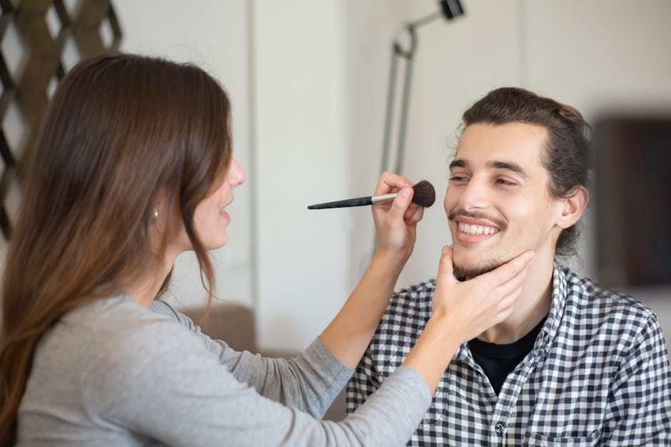 A woman skillfully applies makeup to a man with a makeup brush, highlighting beauty and self-care.