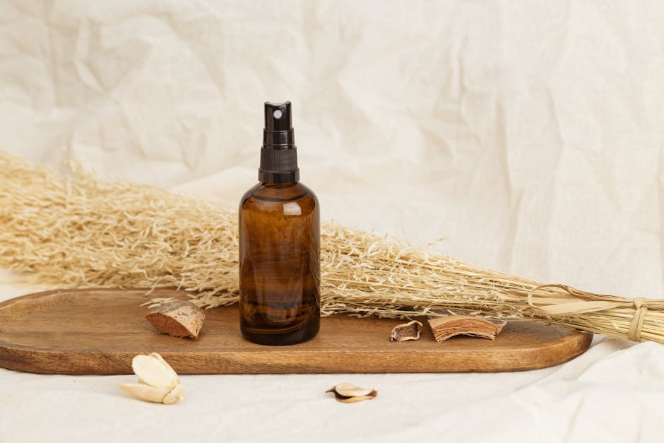 Amber glass spray bottle placed on a wooden tray with dried plants, suggesting natural cosmetics.