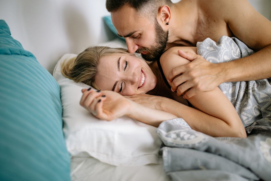 Happy couple embracing in bed, showcasing love and affection in a cozy home setting.