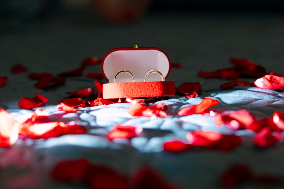 Romantic scene with gold rings in a red box surrounded by rose petals.