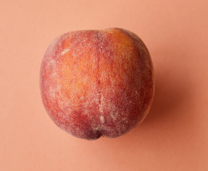 A detailed view of a fresh, ripe peach on a pink background. Perfect for healthy lifestyle themes.