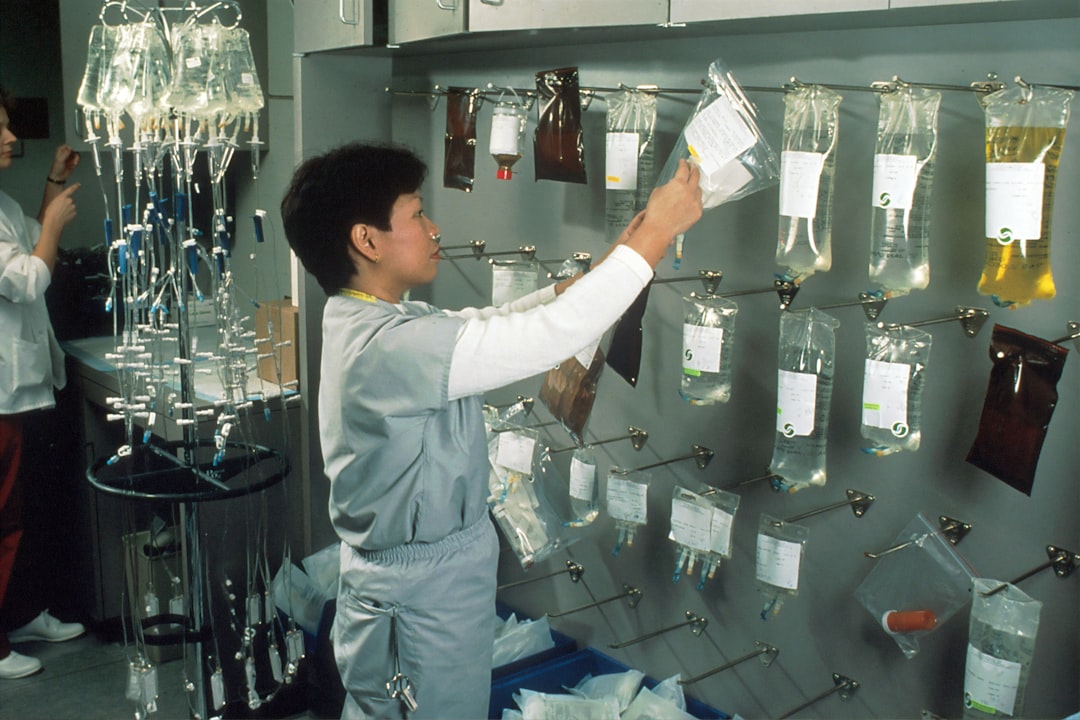 man in white long sleeve shirt pouring water on clear glass bottles