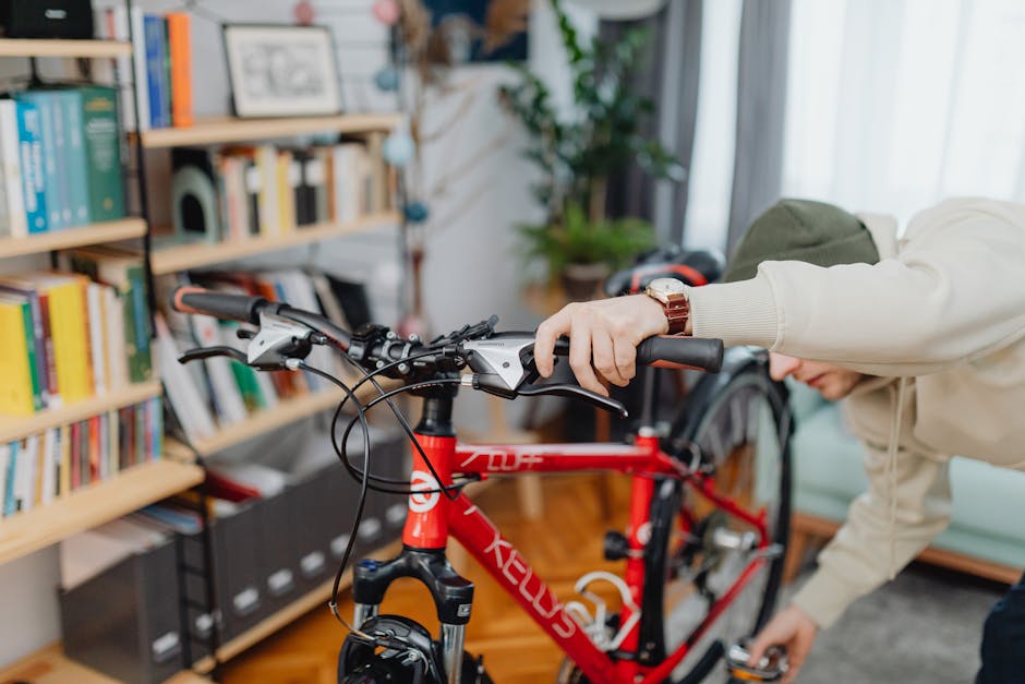 Man adjusting his bicycle indoors next to a bookshelf.