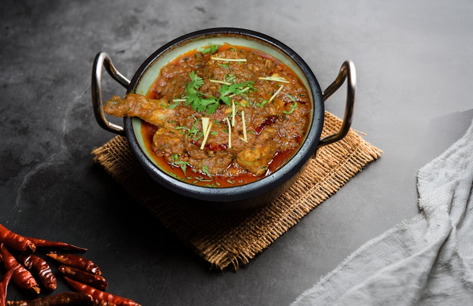 Authentic Indian chicken curry in a bowl with garnish on dark background.