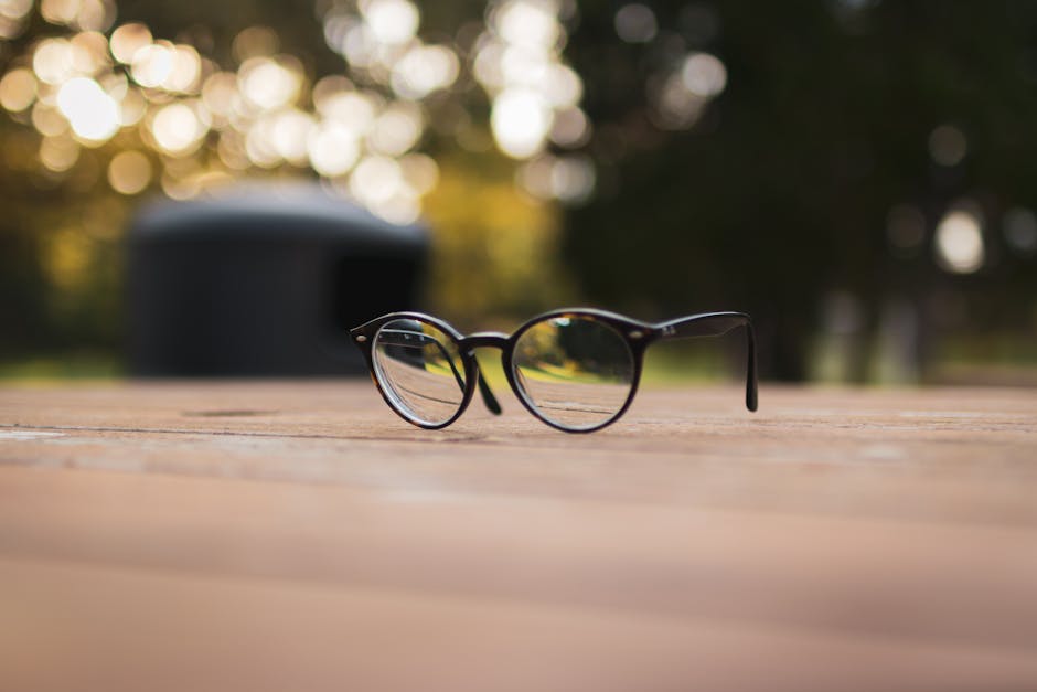 Close-up of stylish eyeglasses on a wooden surface with a blurred bokeh background.