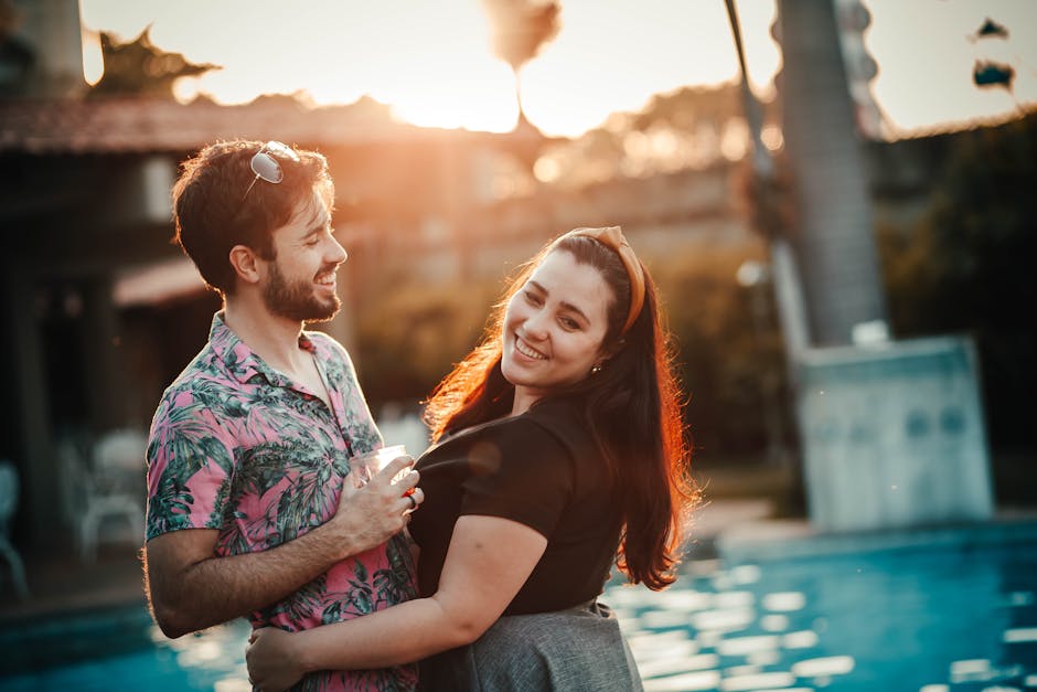 A happy couple shares a warm embrace by the pool during sunset, capturing a moment of romance and joy.