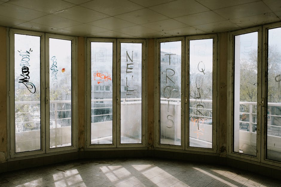 Abandoned building interior with graffiti on windows in an urban setting.