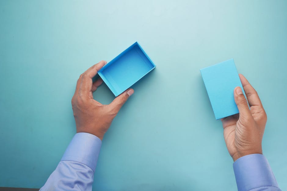 Close-up of a man's hands holding a blue box on a blue background.
