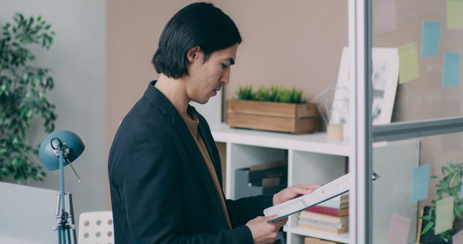 Young man analyzing paperwork in modern office setting.