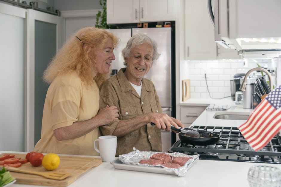 A senior couple enjoys cooking burgers in their modern kitchen, celebrating with joy.